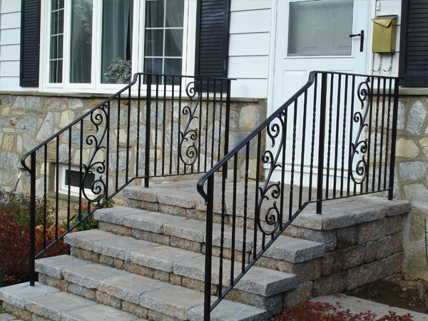 Front stoop and steps edged with two black, stylish wrought iron railings.