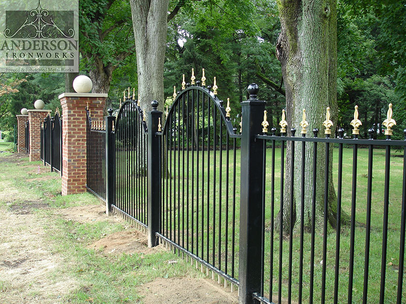 Traditional victorian style wrought iron fence with polished brass post tops